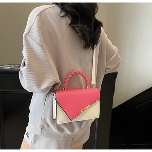 Détail du sac bandoulière bicolore avec poignée torsadée et fermoir métallique