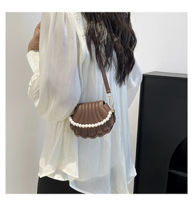 Détail d'un sac marron en forme de coquillage avec perles blanches et fermoir en métal doré