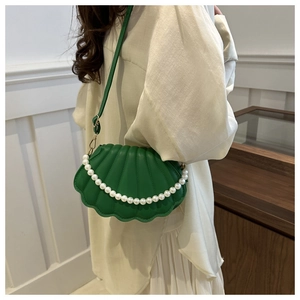 Détail du sac vert en forme de coquillage avec texture plissée et anse en perles