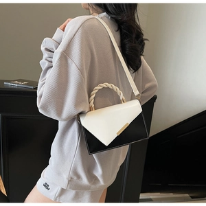 Détail du sac bandoulière bicolore avec poignée tissée blanche et finitions dorées