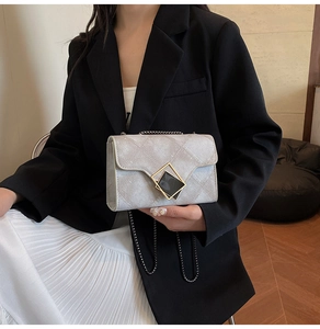 Detail of grey quilted shoulder bag with gold diamond lock on black blazer