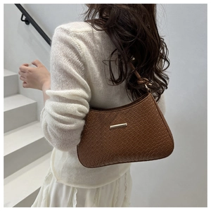 Close-up of brown crocodile pattern shoulder bag with sleek gold metal trim and arc shape