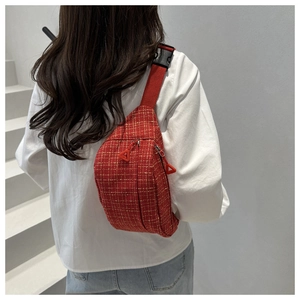 Detailed view of red tweed crossbody bag texture with nylon strap and black buckle