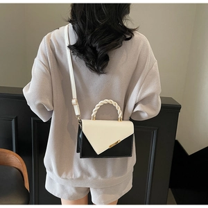 Détail d'un sac bandoulière chic noir et blanc avec garniture dorée et poignée tissée