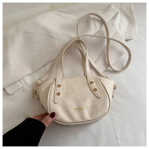 Détail du sac seau en cuir crème avec rivets dorés et logo de marque de mode