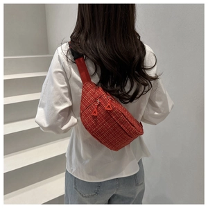 Back view of a red plaid crossbody chest bag with adjustable strap on a model