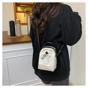 Compact nylon crossbody bag with drawstring closure shown in a lifestyle setting