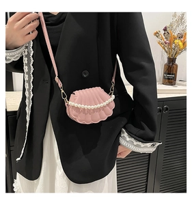 Détail du sac bandoulière en forme de coquillage avec chaîne perle et coutures nervurées