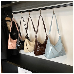Row of pleated tote bags in five colors with metal chain details and glossy finish
