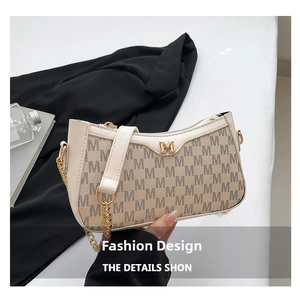 Macro shot of beige monogram handbag with gold M buckle and metal chain strap detail