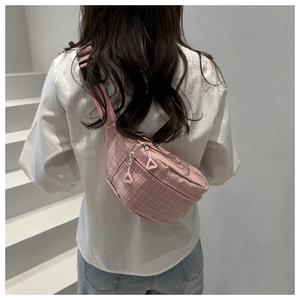 Close-up of pink checkered waist bag with double zippers and adjustable strap worn on back
