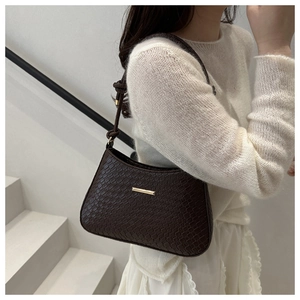 Detail of dark brown croissant bag with crocodile texture and gold hardware accent