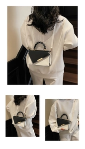 Détail du sac bandoulière bicolore avec garniture dorée et poignée tressée sur modèle