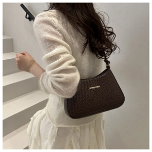 Detail of minimalist dark chocolate woven hobo bag with gold hardware worn by a model