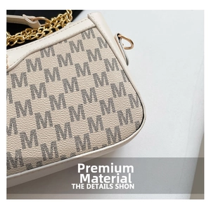 Detail of beige crescent bag featuring M-pattern texture and gold chunky chain strap