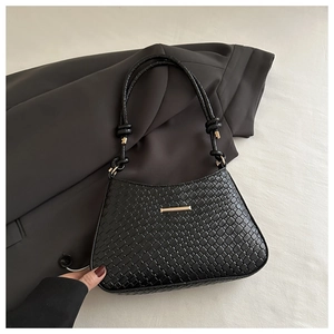 Close-up of black woven leather texture and elegant gold buckle on minimalist handbag
