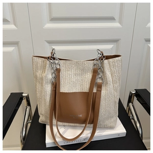 Close-up of woven straw tote bag featuring brown leather pocket and silver chain strap
