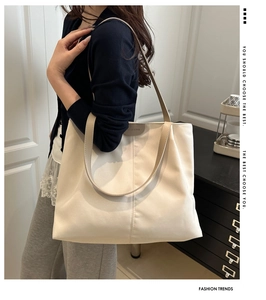 Model wearing a large cream tote bag showing capacity and stylish shoulder strap detail