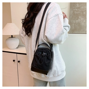 Detail of waterproof nylon crossbody bag featuring drawstring closure and leather base