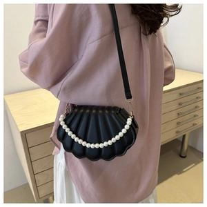 Détail du sac à bandoulière noir en forme de coquillage avec poignée de perles blanches