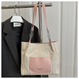 Detail of woven tote bag with pink leather pocket and metal chain strap accent