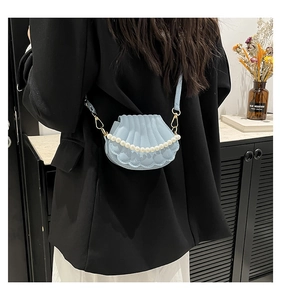 Détail du sac coquille bleu clair avec chaîne en perles et texture sur sac bandoulière