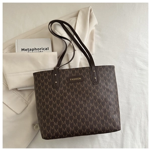 Detail of a brown tote bag with M letter prints and Fashion logo on an office blazer