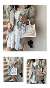 Detail of floral embroidery and grey logo strap on an elegant off-white tote bag
