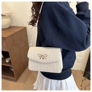 Close-up of beige woven crossbody bag featuring a golden bow buckle and V-shaped texture