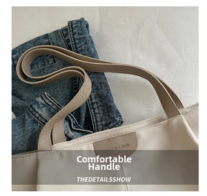 Close-up of off-white canvas tote with brown leather handles and a fashion leather patch