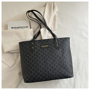 Detail of the dark gray tote bag showing repetitive letter M pattern and black FASHION tag