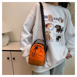 Detail of orange canvas and brown PU leather crossbody bag with drawstring closure