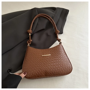 Detailed view of brown woven underarm bag with knot strap and gold metal clasp