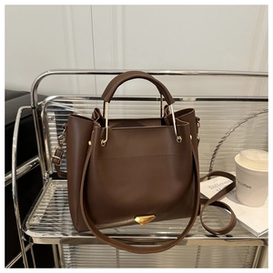 Detailed view of dark brown leather bucket bag with gold triangle logo and strap