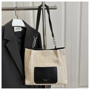 Detail of herringbone straw tote bag featuring black leather pocket and silver chain handle