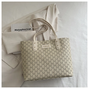 Macro detail of cream tote bag with letter print and metal fashion brand plate