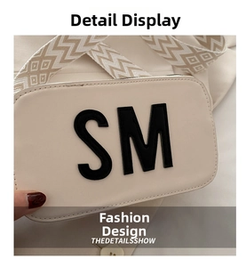 Détail du sac beige avec écusson lettre SM noire et bandoulière tissée géométrique