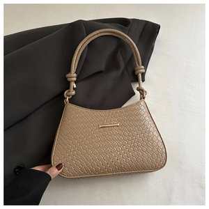 Detail of woven texture underarm bag with gold metal clasp and knotted rope handle