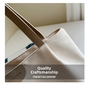 Close-up of off-white canvas tote showing brown faux leather strap and quality stitching