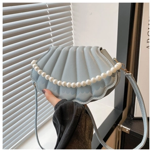 Détail du sac coquillage bleu clair avec chaîne en perles et texture nervurée