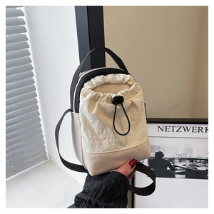 Detail of beige nylon drawstring water bottle bag with black adjustable strap and handle