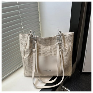 Dettaglio borsa tote intrecciata con tasca in pelle bianca e tracolla a catena in luce naturale