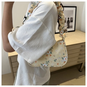 Detail der floralen Hobo-Tasche mit geriffeltem Griff und Vintage-Print auf Holz