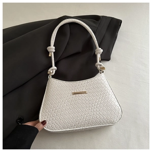 Detail of white woven texture underarm bag with gold metal clasp and knot shoulder strap