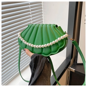 Vue détaillée du sac vert en forme de coquillage avec texture plissée et anse en perles