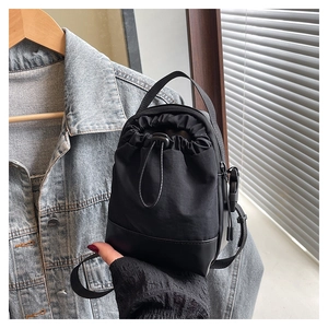 Close-up of lightweight black drawstring crossbody bag with durable nylon and leather base