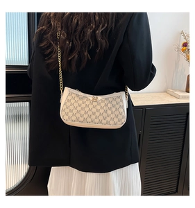 Detail of monogram patterned shoulder bag with gold M logo and chic metal chain strap