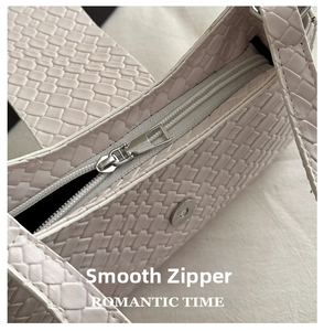 Detailed close-up of premium woven leather texture and smooth metal zipper on shoulder bag