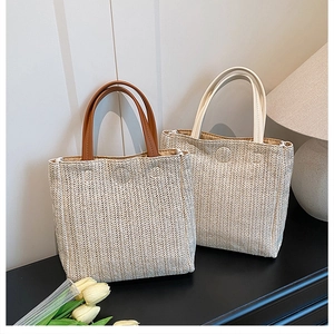 Detail of woven straw tote bags with herringbone texture and dual PU leather handles