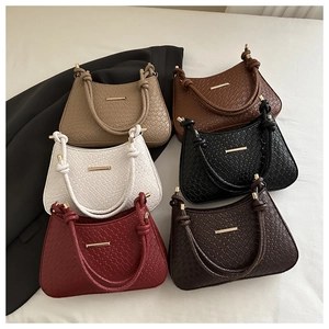 Flat lay of woven shoulder bags in six colors with gold metal detail and knotted handles